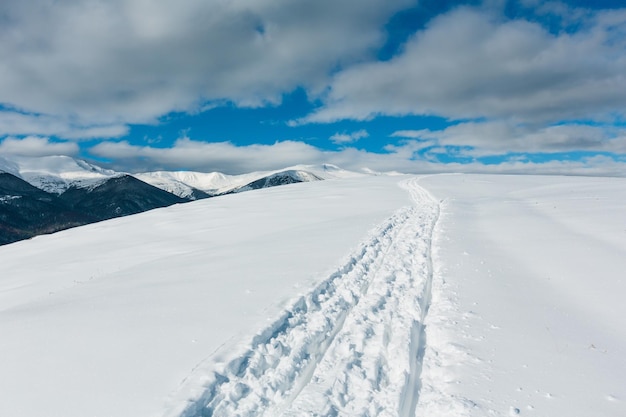 Sledge trace and footprints on winter mountain hill top