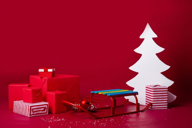 Санки с рождественскими подарками на красном фоне