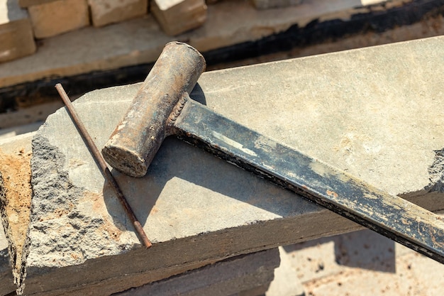 A sledgehammer or hammer made by workers licks on a concrete block at a construction site Working tool closeup