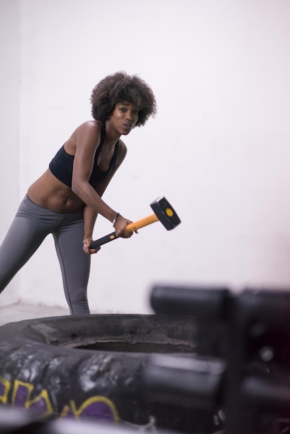 Sledgehammer Tire Hits Afro-Amerikaanse vrouw training in sportschool met hamer en tractorband