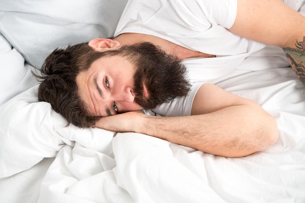 Концепция расстройств сна Какая длинная ночь Мужчина бородатый хипстер, имеющий проблемы со сном Парень, лежащий в постели, пытается расслабиться и заснуть Методы релаксации Нарушения сна и бодрствования