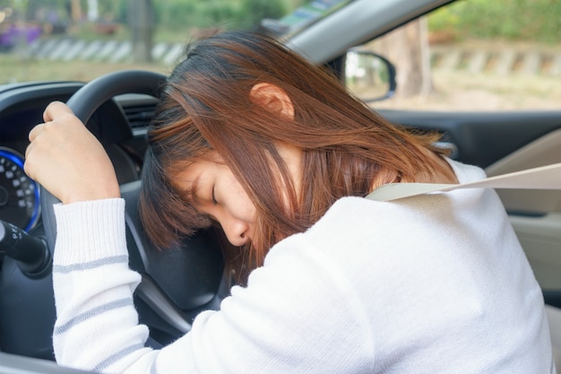 写真 睡眠、疲れ、目を閉じて長い時間の旅行の後彼女の車を運転する若い女性