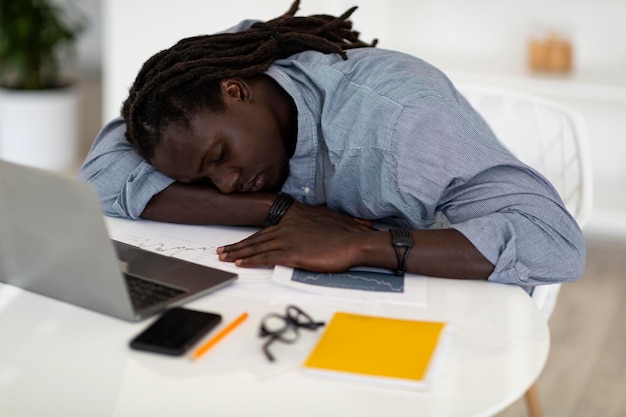 Sleep at work tired african american man napping at desk with
laptop