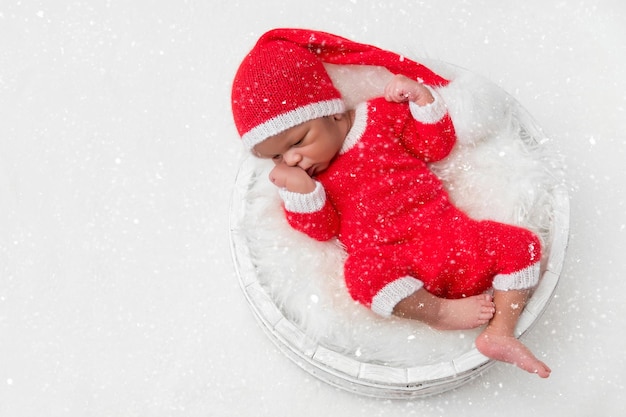 クリスマスサンタ帽をかぶった寝台の生まれたばかりの赤ちゃん