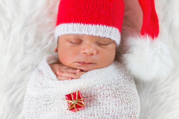 クリスマスサンタ帽をかぶった寝台の生まれたばかりの赤ちゃん