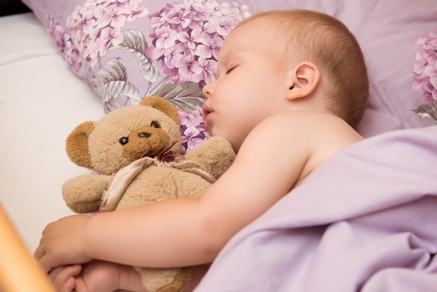 Sleeping baby on the bed with Teddy