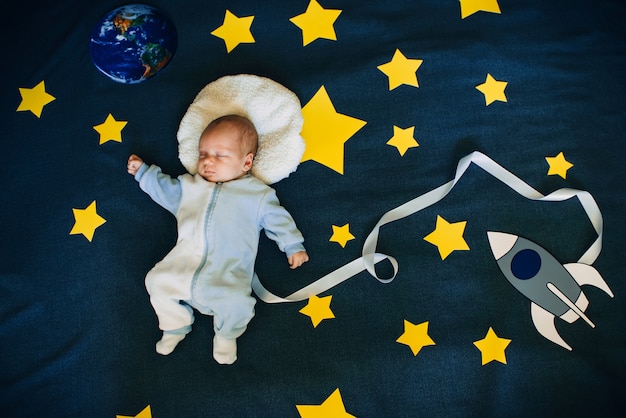 Sleeping baby boy astronaut on a background of the sky