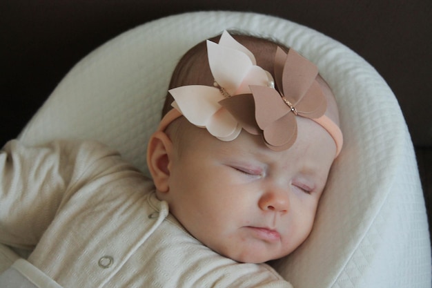 Sleeping baby girl lying on her back in a bow tie on her head