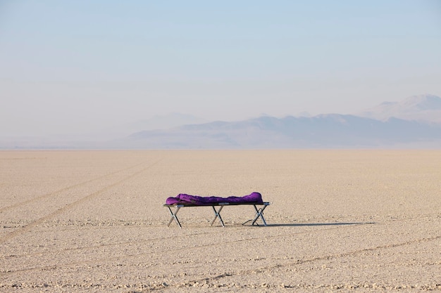 Sleeping bag on cot in vast barren desert dawn