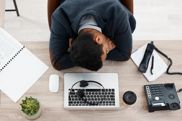 Sleeping business man and call center work from above with fatigue in office Telemarketing contact us and phone consultation worker feeling tired and overworked at company with deadline and sleep