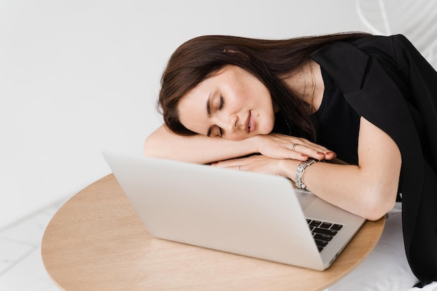 Sleeping girl with laptop on the table on white background Tired young woman have a break at work and sleeping and relaxing at laptop on workplace due to overtime work