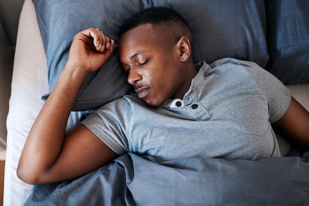寝るのは、一人で家で休んでいる間にベッドで寝ているハンサムな若い男の最高のクロップドショットです