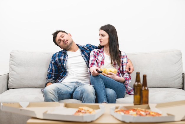 The sleeping man and a woman sit on the sofa on the white wall background