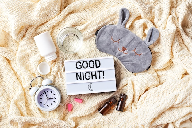 Photo sleeping mask, alarm clock, earplugs, essential oils and pills. healthy night sleep creative concept. flat lay, top view. good night, sleep hygiene, insomnia