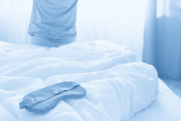 Sleeping mask on a bed with stretching woman in the background