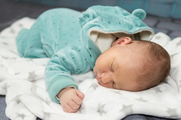 Sleeping newborn baby on a blanket with a teddy