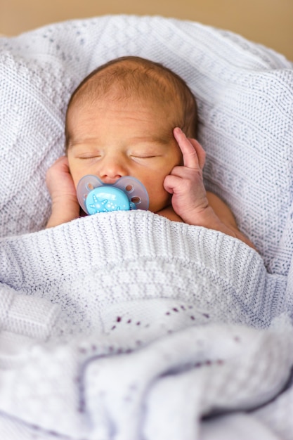 Sleeping newborn baby boy with a pacifier. Babyface close-up.