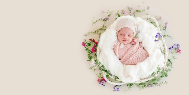 Sleeping newborn baby girl wrapped in a basket with flowers