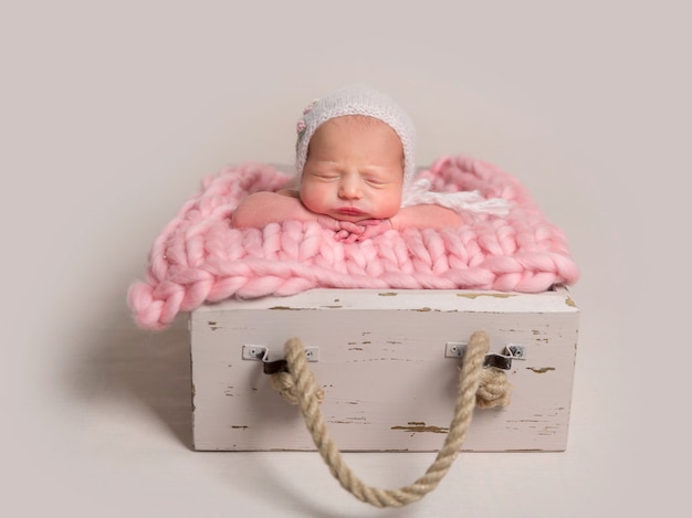 Sleeping newborn baby with chubby cheeks lying in box on rug