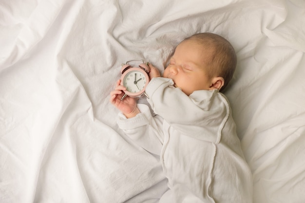 Sleeping newborn baby in a wrap on white blanket