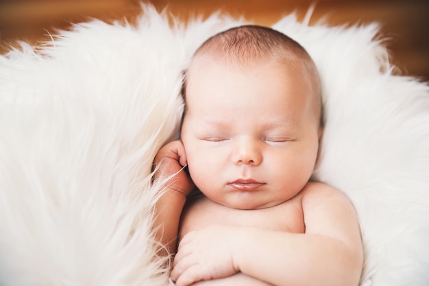 Sleeping newborn baby in a wrap on white blanket