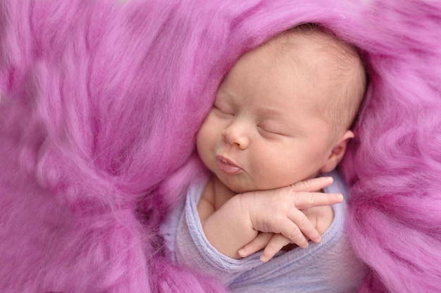 Sleeping newborn girl on a pink wool background closeup