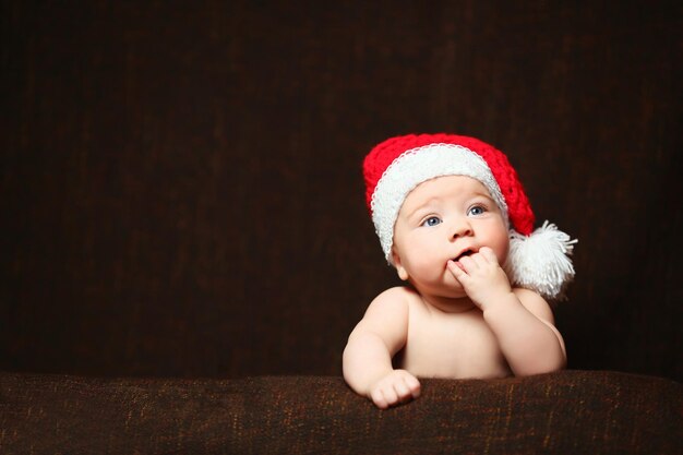 Sleeping two week old newborn baby boy wearing a crocheted Santa hat with snowman plush toy