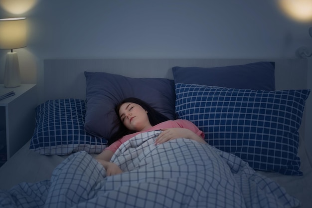 Sleeping young brunette girl on bed in night