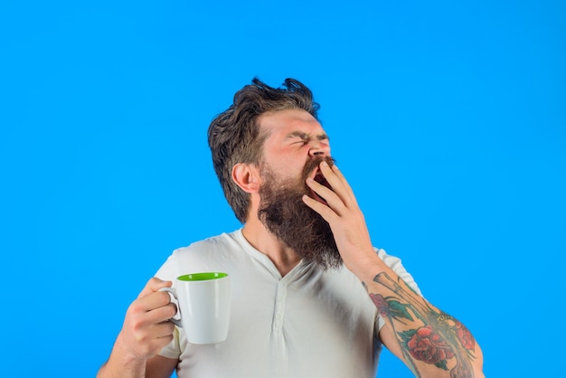 Sleepy bearded man drinks coffee. monday morning. breakfast, tea, cup, mug. morning routine.