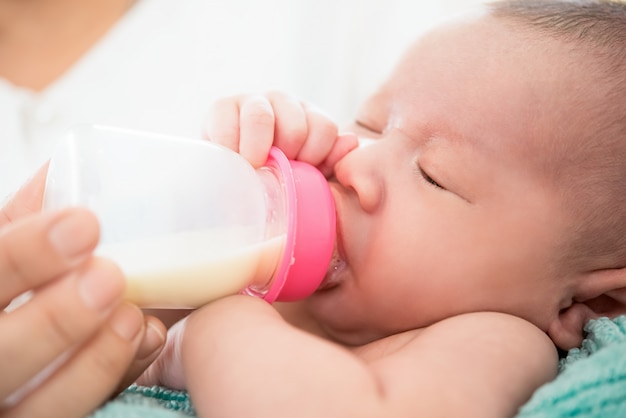 Sonnolento carino neonato beve il latte dalla bottiglia
