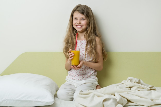 Sleepy girl in pajamas sits in bed at home