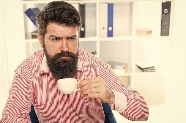 Sleepy halfawake hipster drink cup of coffee in workplace caffeine