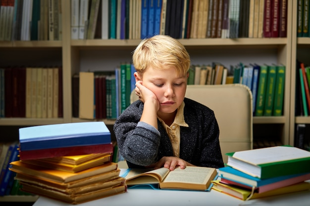 sleepy little boy tired of learning doing homework reading book, studying preparing for exam test, literature research, children education concept