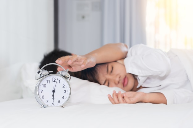 眠そうな男は、騒々しい目覚まし時計で悩まされている女性の横に目覚まし時計をオフにしようとする