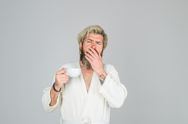 Sleepy man yawning tired sleepy man with cup of coffee in hand coffee morning man in bedroom yawning