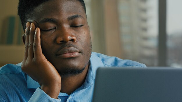 Sleepy overworked tired african american man employee manager businessman fall asleep at office desk