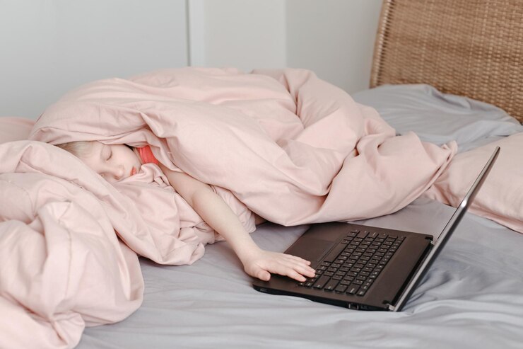 Photo 睡覺疲倦的女孩躺在床上,在毯子下,在虛擬的網上學校課堂上學習