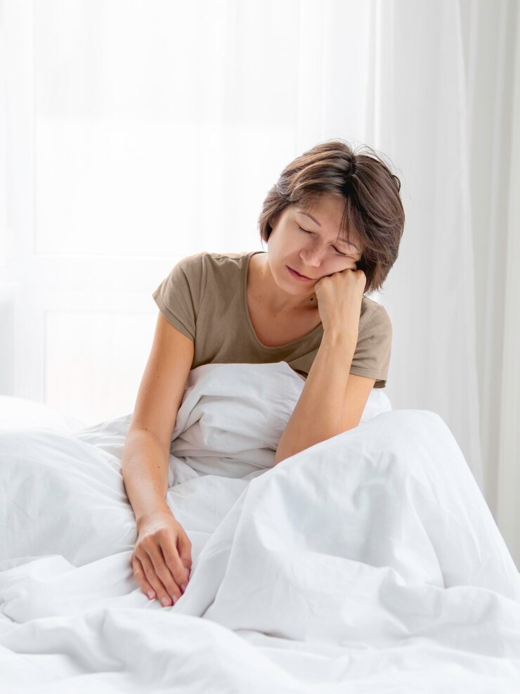 Photo 眠い女性はベッドに座っています目覚めるのが難しいです女性は十分な睡眠を得ていません