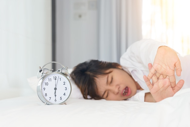 Sleepy woman trying turn off alarm clock in the morning