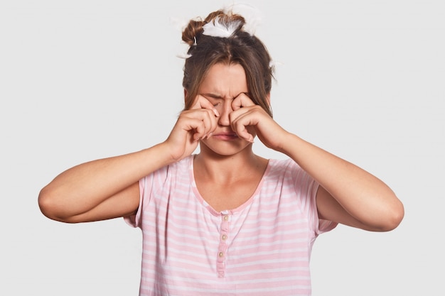 Sleepy woman wakes up early, rubs eyes as wants to sleep