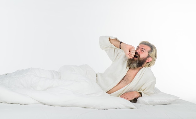 Sleepy yawning man tired sleepy man in bathrobe morning routine man in bedroom morning and wake up