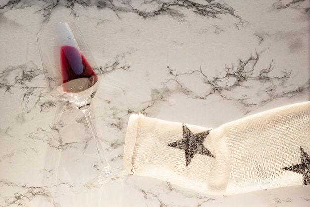 Sleeve of sweater holds glass of red wine on marble table