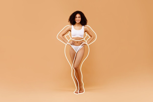 Slender african american lady posing in white underwear over beige