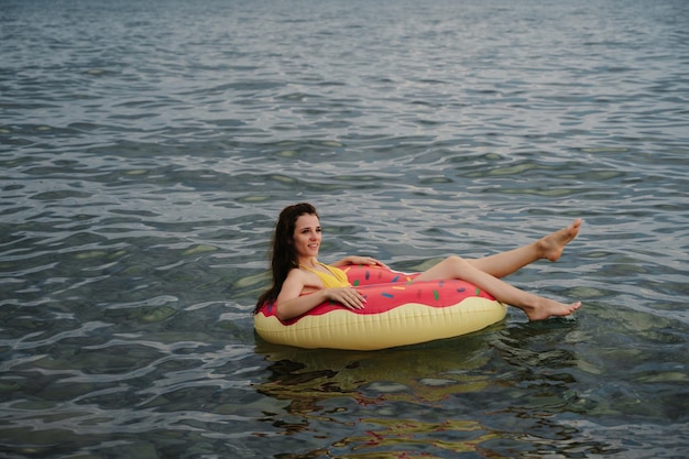 Slender girl swims on an inflatable circle in sea in summer on vacation