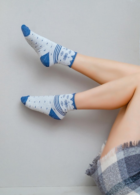 Slender legs of a woman in socks bent to her knees on a gray background