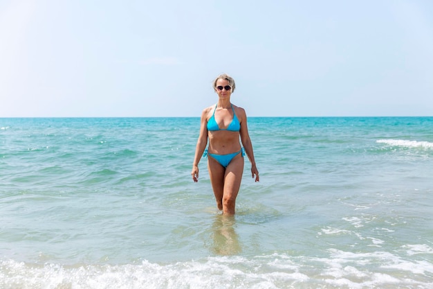 Слабая женщина в синем купальнике купается в море в солнечный день Туристические путешествия и отдых на курорте