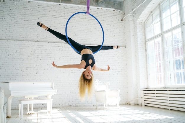 Slender woman is engaged in aerial gymnastics with a circle