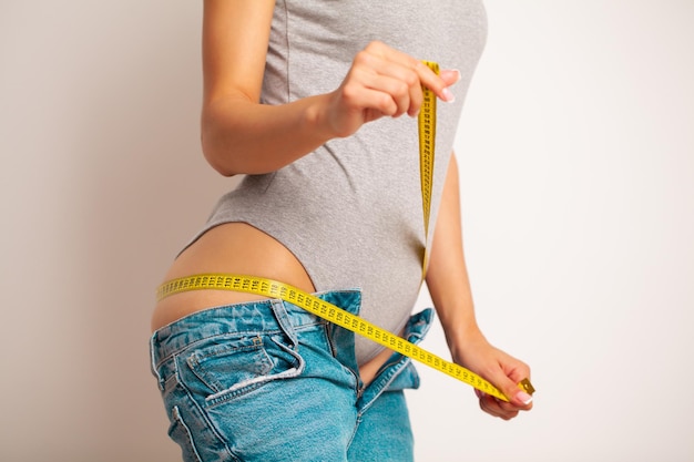 A slender woman measures the size of her waist