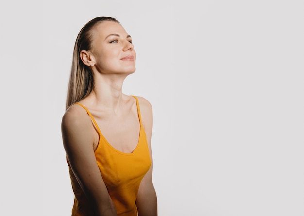 A slender young woman in a thin yellow Tshirt on a white background