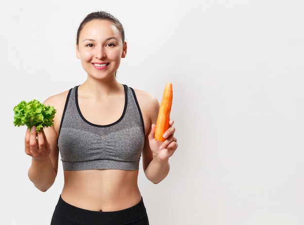 Slender young woman with a beautiful figure holds vegetables in her hands